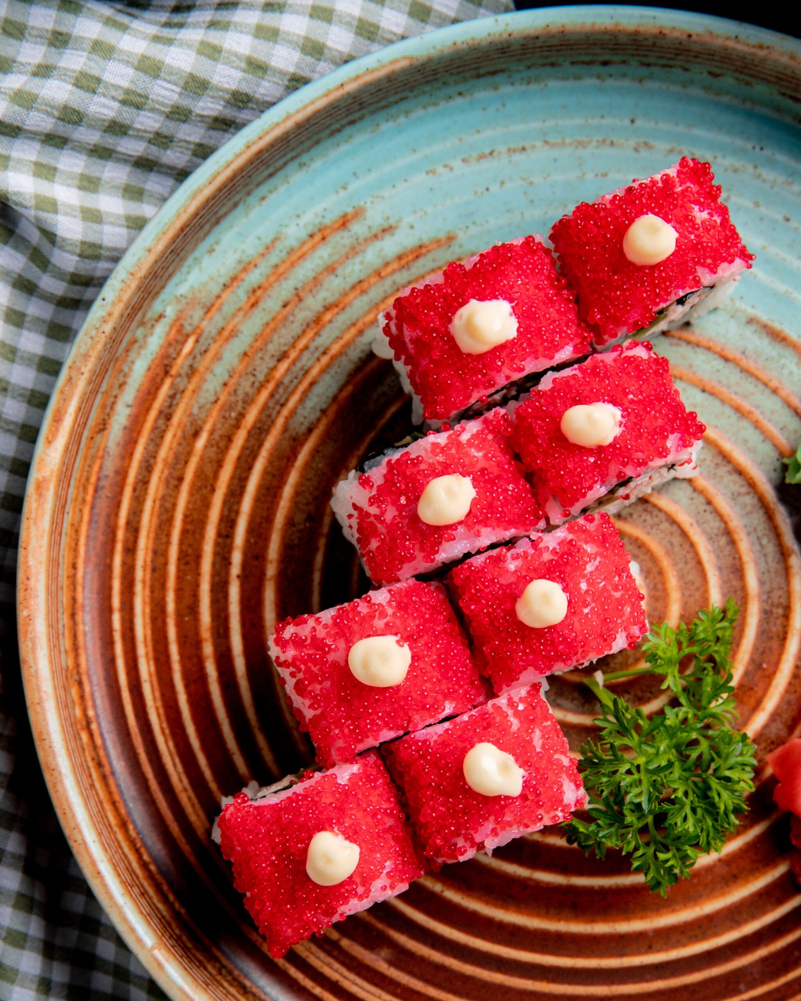 top view of sushi roll with crab avocado covered with red caviar with ginger and wasabi on a plate